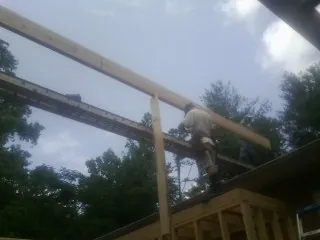 Carpenter setting a ridge beam over a new addition frame — Ice Dam Removal by Roofing Brothers in Ronan