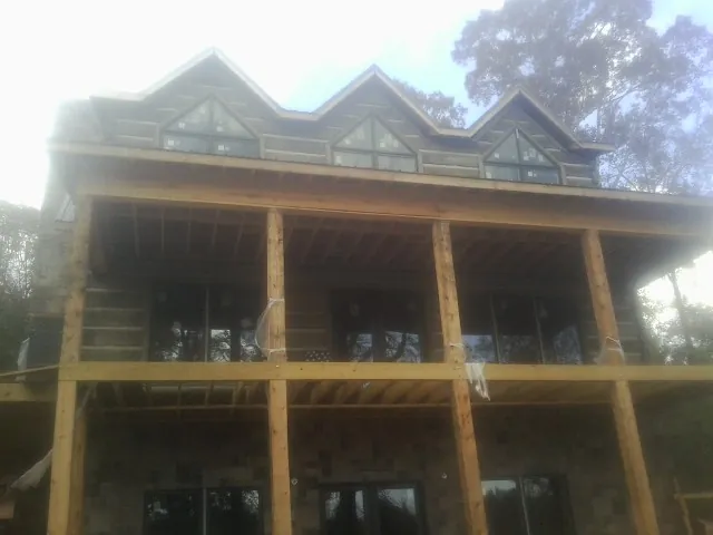 Dormers and porch framing on a large log home under construction — Roof Coating work by our crew in Ronan