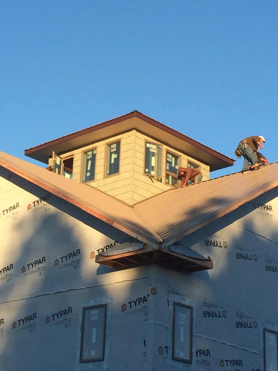 Roofers working around a rooftop cupola on a new metal roof at sunset — Roof Waterproofing in Ronan by Roofing Brothers